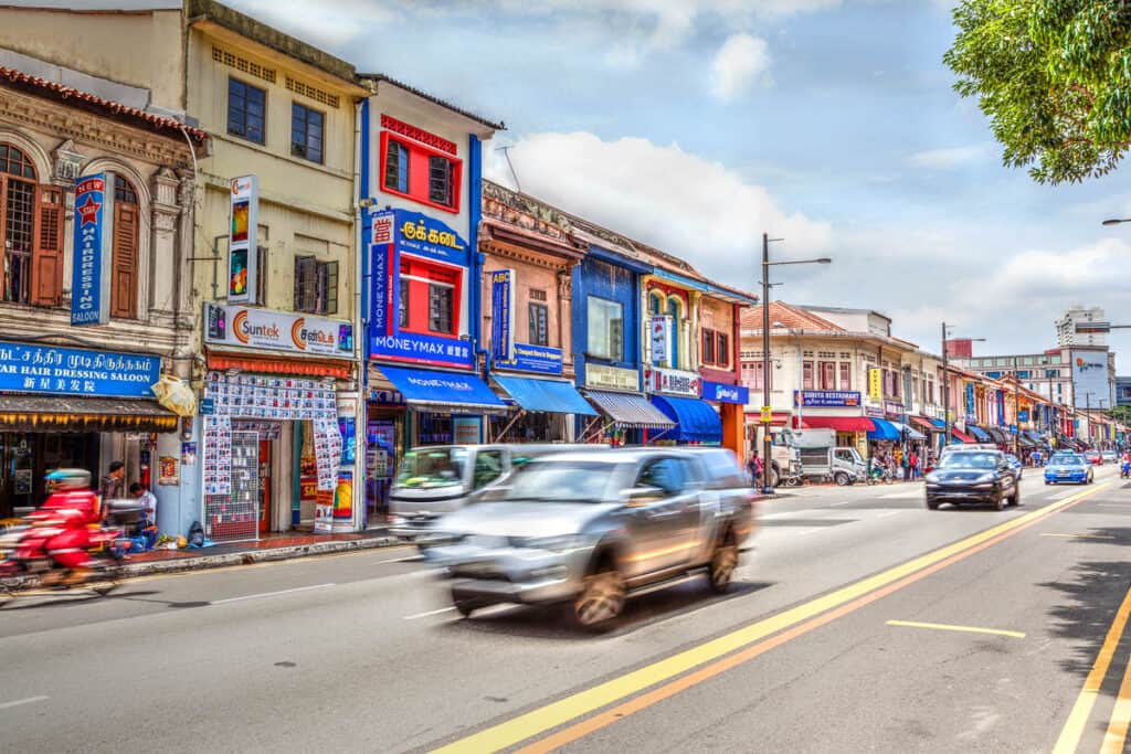 Street in Little India with shophouses and cars. 