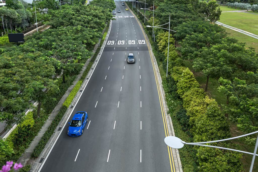 Road from Changi airport with four lanes and cars on them in Singapore.