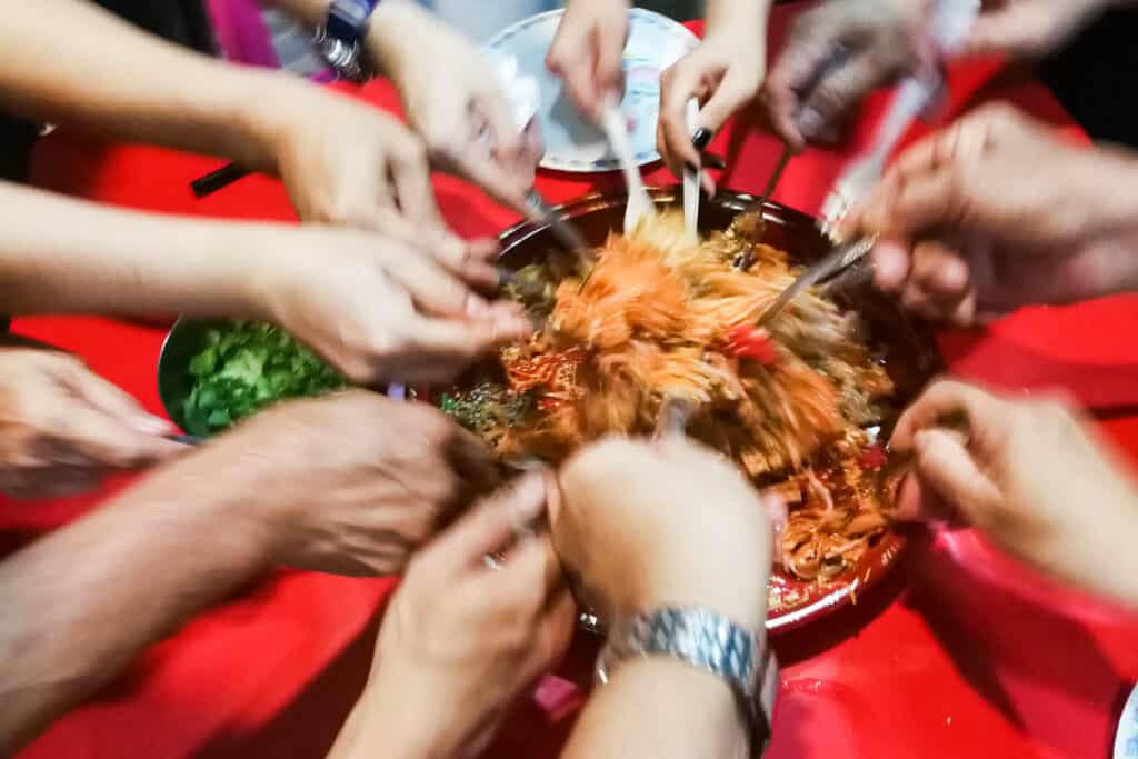 Motion blur of people tossing yusheng during Chinese New Year.