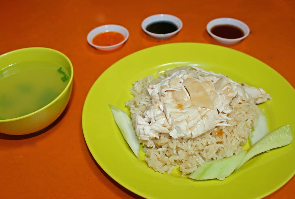 Chicken Rice with soup and sauces on orange table.