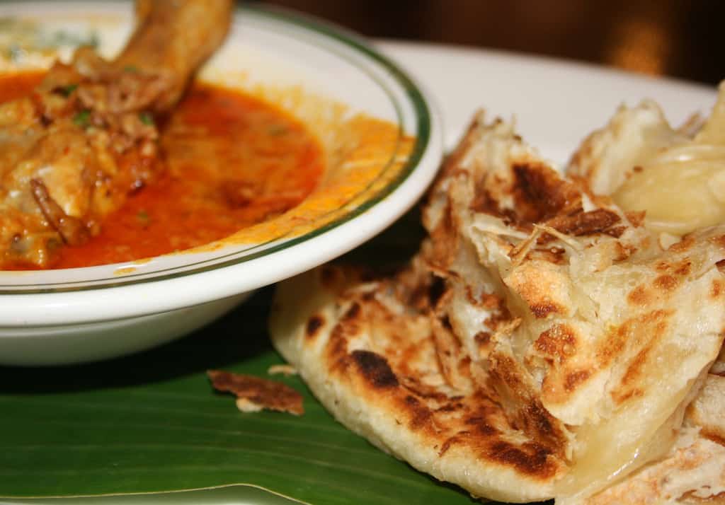 Close up of roti prata with a bowl of chicken curry. 