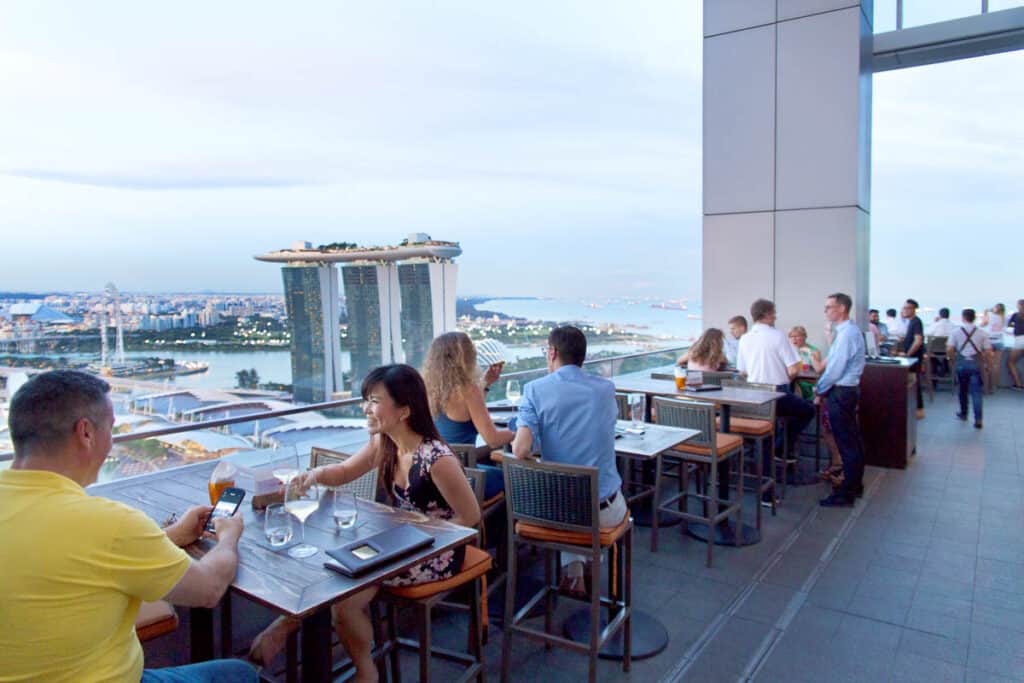 People sitting on Terrace at Level 33 bar with view of Marina Bay Sands. 