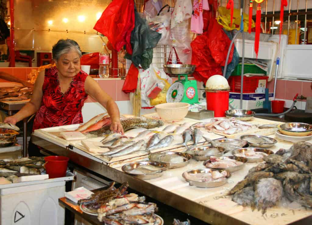 Woman displaying fish in a Singapore wet market. 
