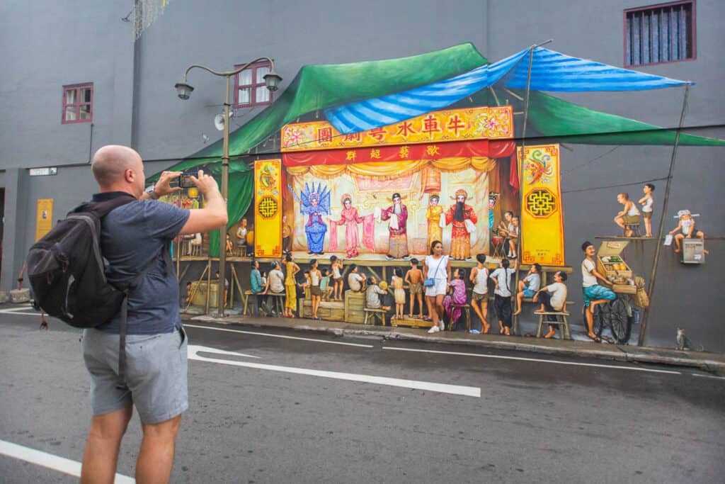 Man taking a photo of a mural on a Singapore tour. 