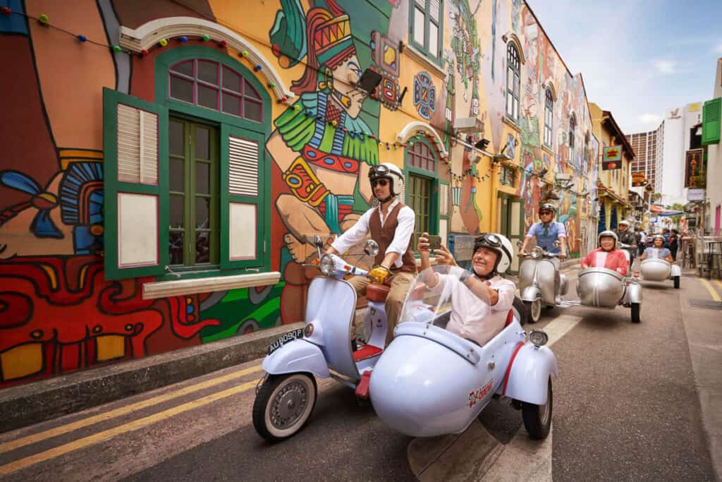 People riding in a sidecar on a Singapore street.