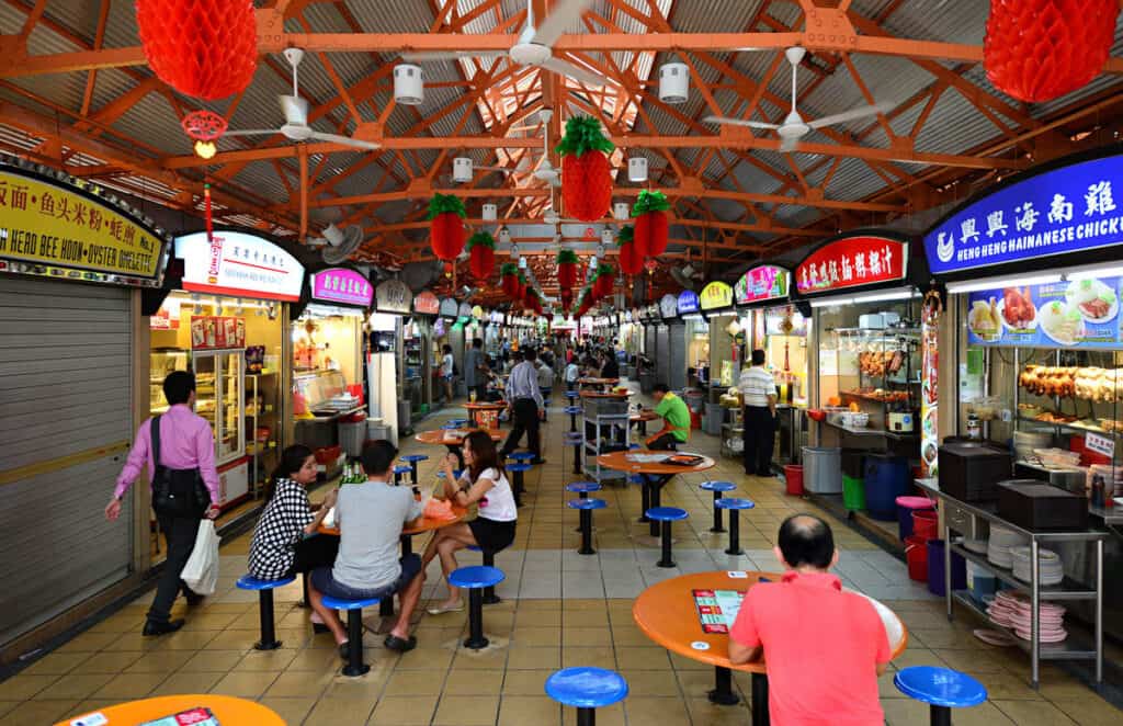 Interior view of Maxwell Food Centre showing food stalls and people eating.
