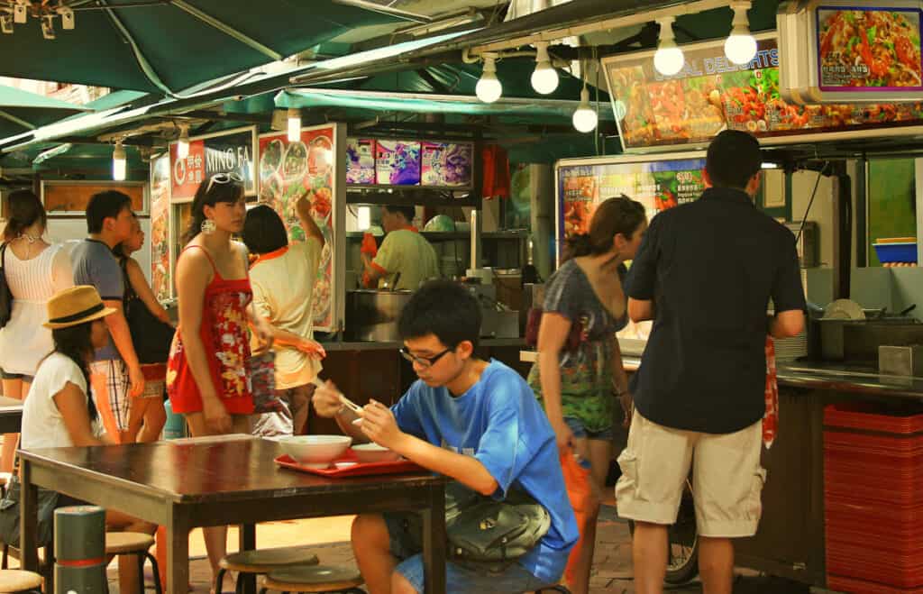 Scene from a Singapore hawker centre showing people eating and browsing stalls. 