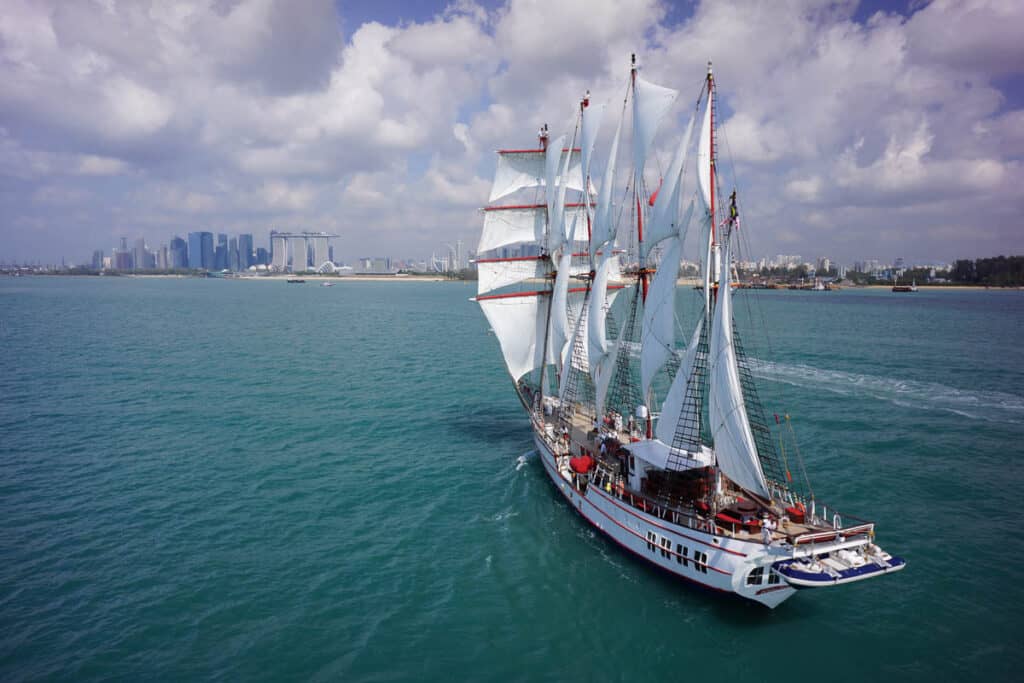Tall ship the Royal Albatross at sea with the Singapore skyline in the background. 