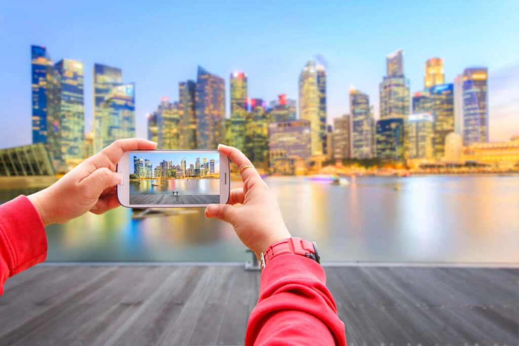 Smartphone photographing landscape of the Singapore financial district buildings.