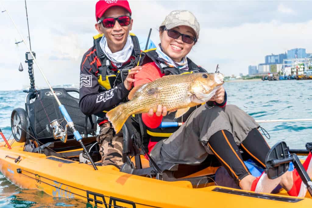 Couple on kayak fishing tour with fish. 