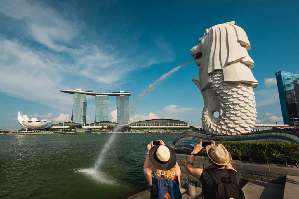 Tourists taking photos on phone at Merlion Singapore.