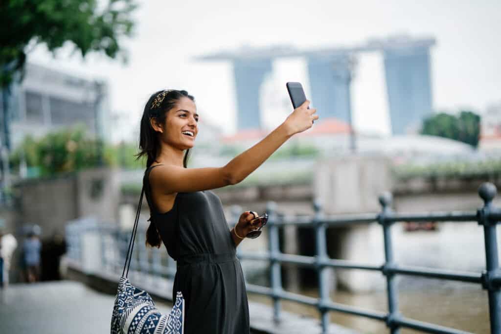 Woman taking selfie with Marina Bay Sands in background. 