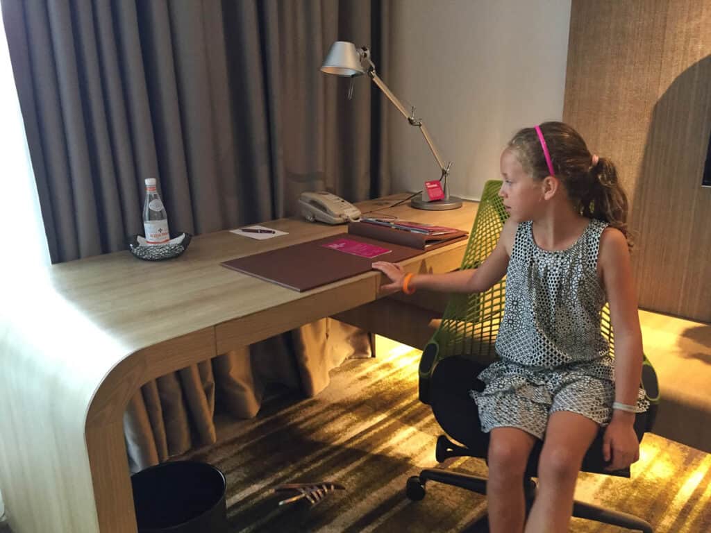 Girl sitting at desk in Crowne Plaza Changi Airport room.