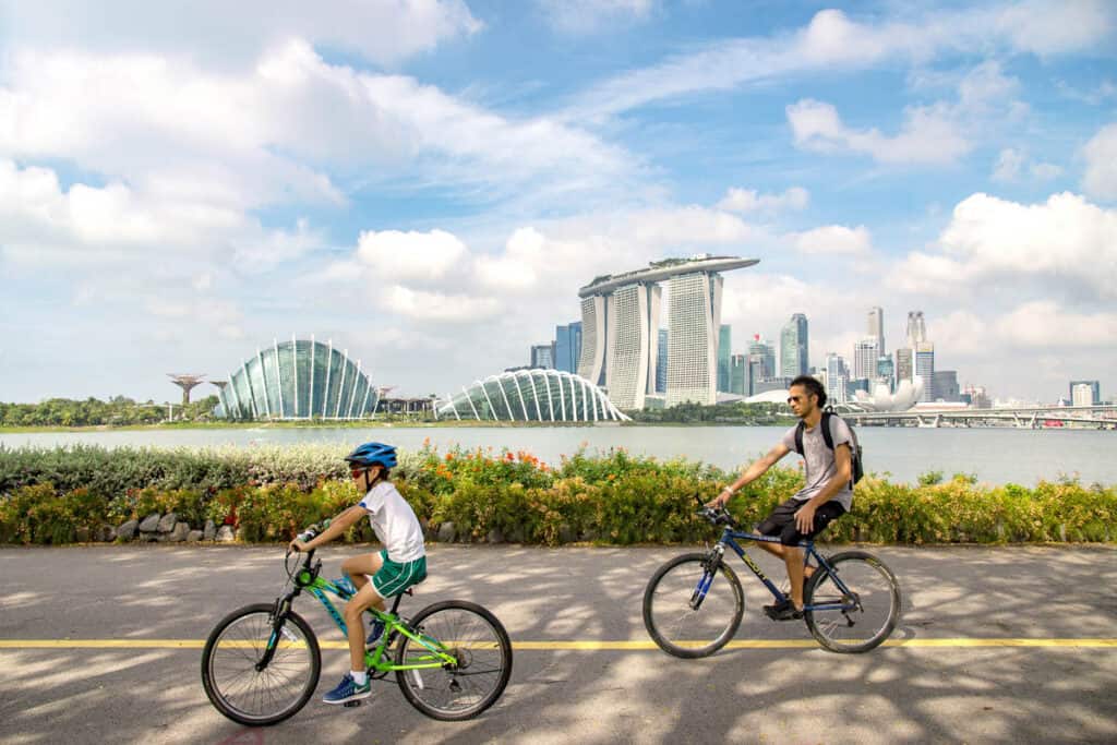 Father and son cycling in Singapore with Marina Bay Sands behind. 