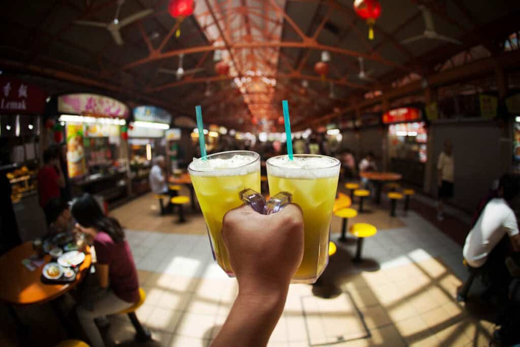 Man holding iced drinks at a hawker centre in Singapore.